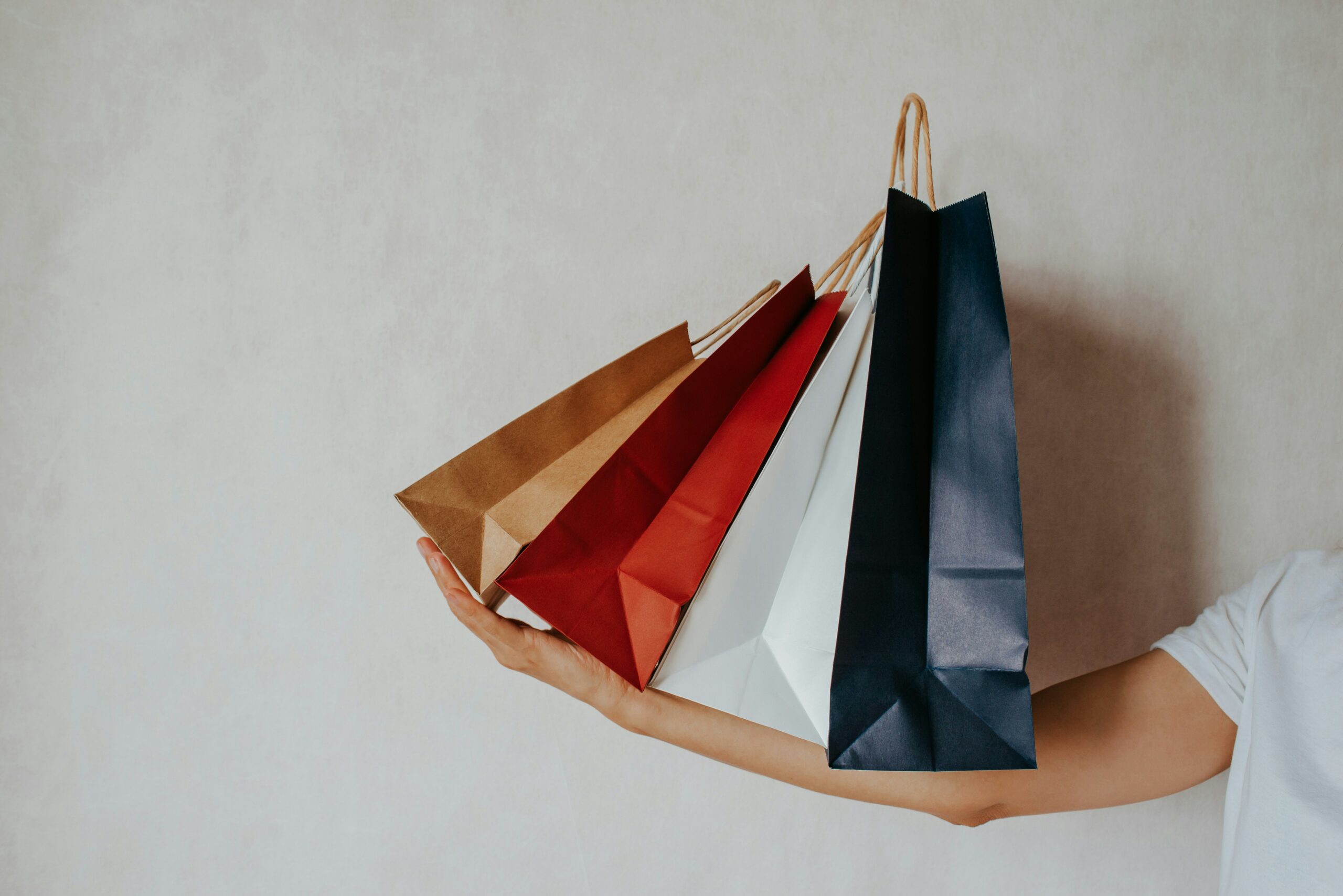 Person holding colourful shopping bags – illustrating irrational consumer decision-making Person holding colourful shopping bags – illustrating irrational consumer decision-making